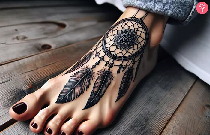 A black dreamcatcher tattoo on the foot of a woman