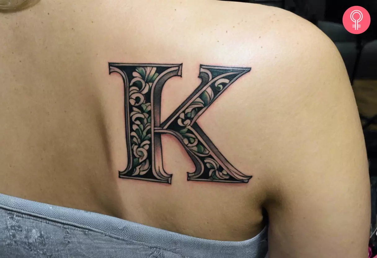 A bold fancy K tattoo on the back shoulder