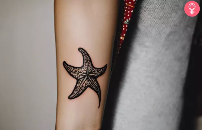 A woman showing a starfish tattoo on her forearm