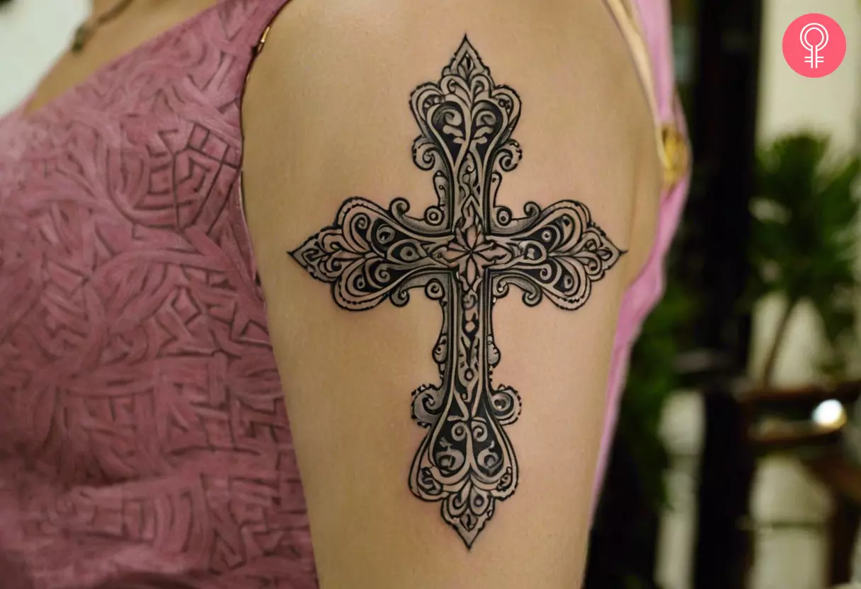 A woman with a filigree cross tattoo on her upper arm