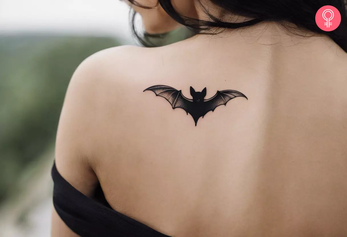 A black and white flying bat tattoo on a woman’s back