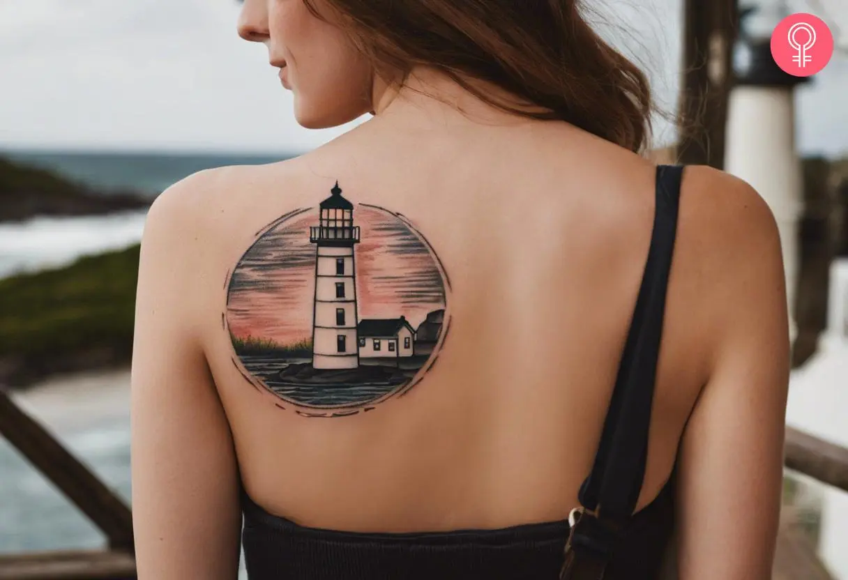 A scenic lighthouse tattoo on the back of a woman’s shoulder