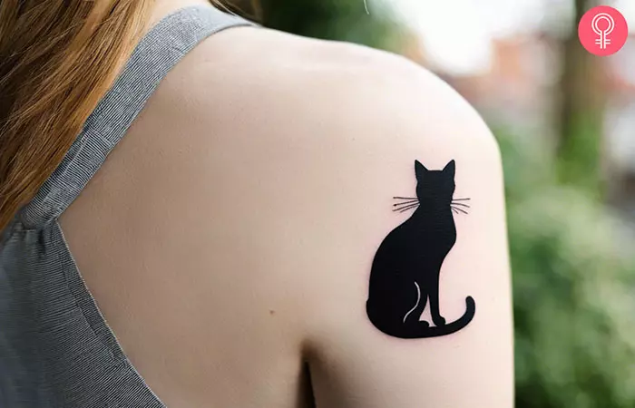 A minimalist cat tattoo on the back of the shoulder