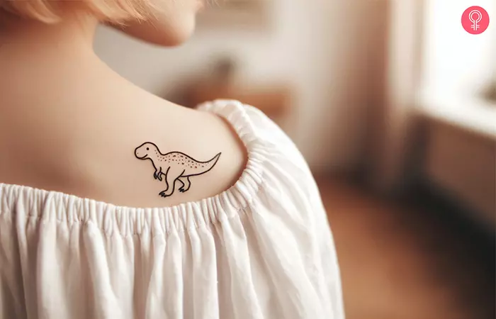 A woman with a minimalist dinosaur tattoo on her shoulder blade