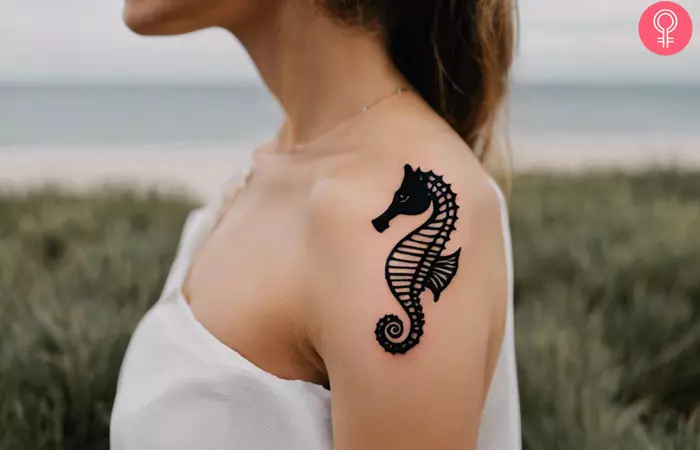 A woman with a minimalist seahorse tattoo on her upper arm