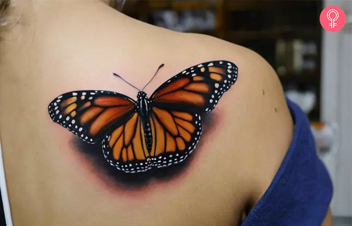 A realistic monarch butterfly tattoo on a woman’s upper back