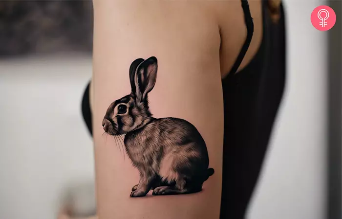 A woman with a realistic rabbit tattoo on the upper arm 