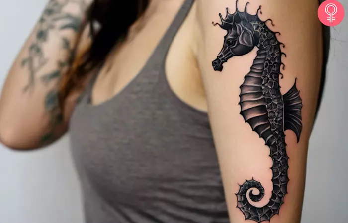 A woman with a realistic seahorse tattoo on her upper arm