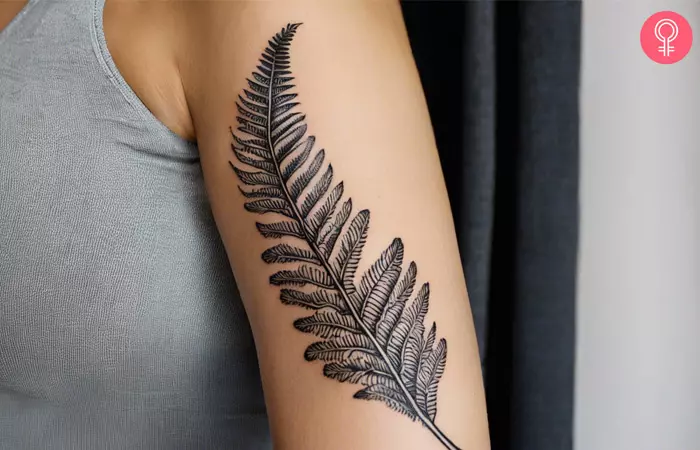 A silver fern tattoo on the upper arm of a woman