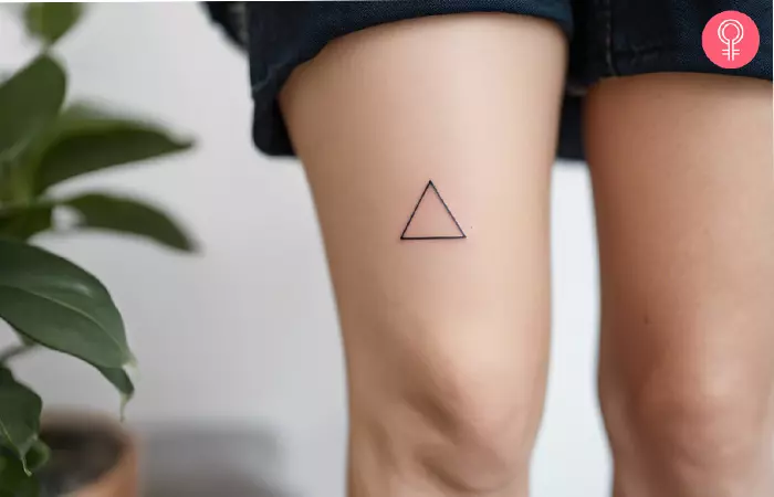 A small above knee tattoo of a triangle