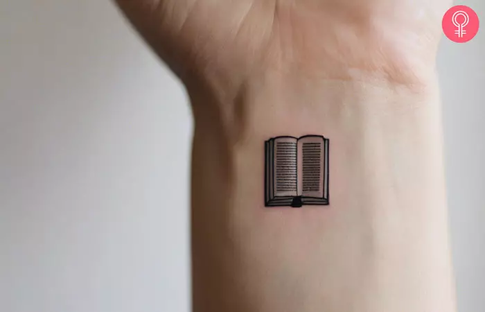 A small book tattoo on a woman’s wrist