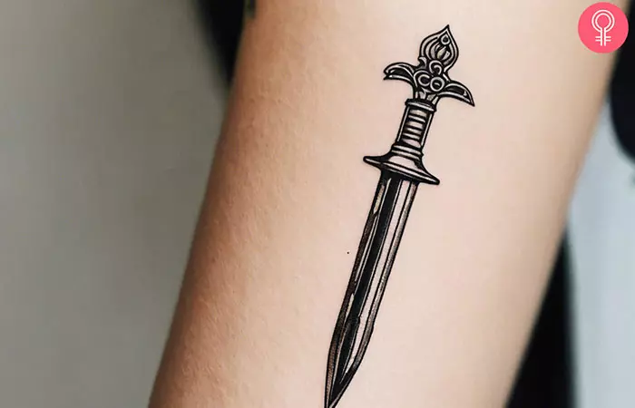 A woman with a small dagger tattoo on her forearm