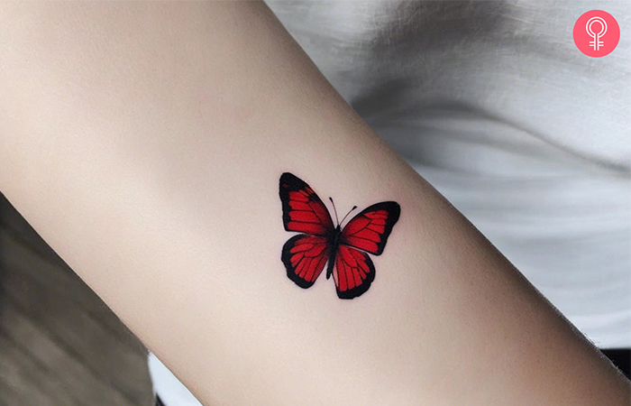 Woman with small red butterfly tattoo on her forearm