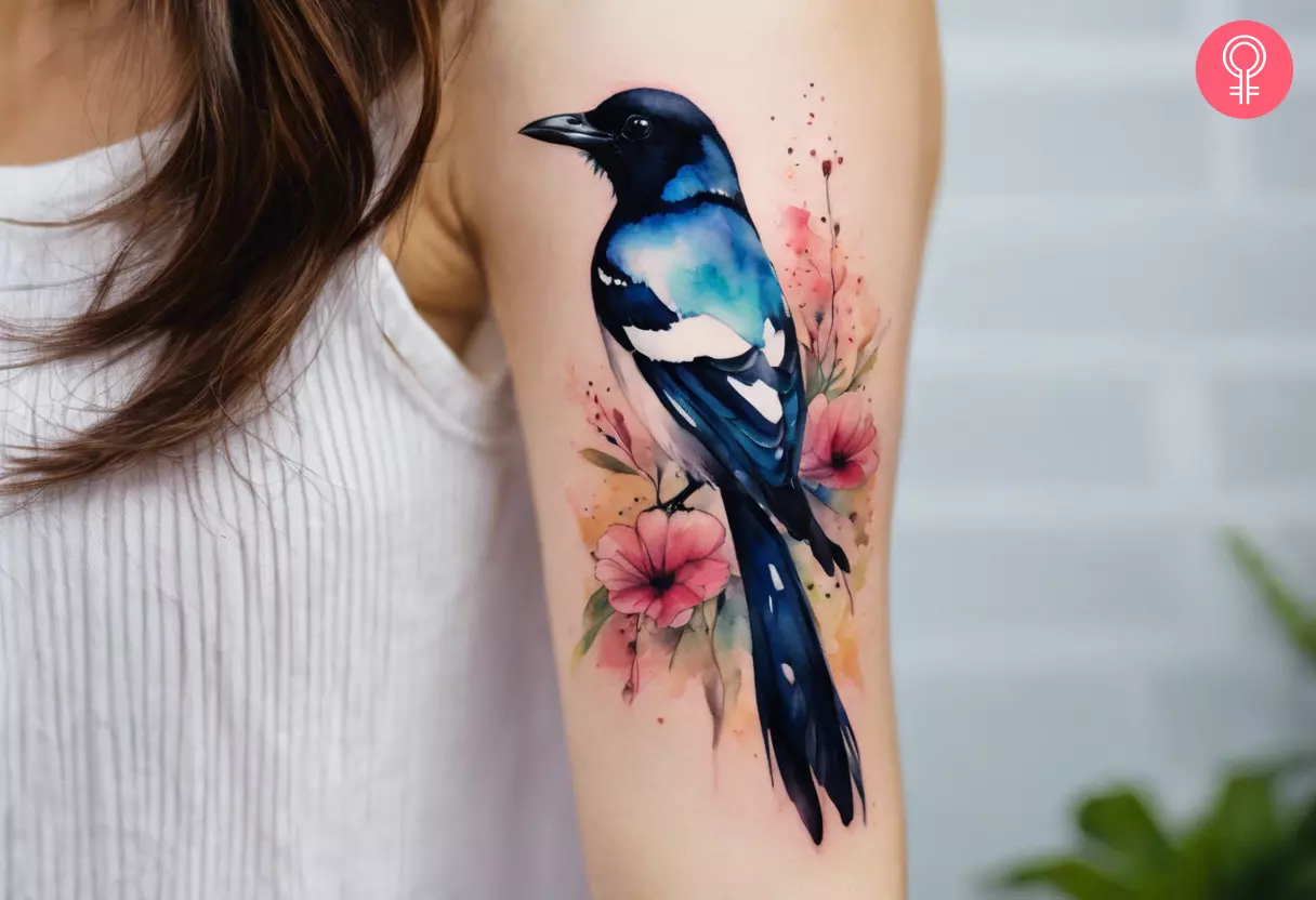 Watercolor magpie tattoo on the upper arm