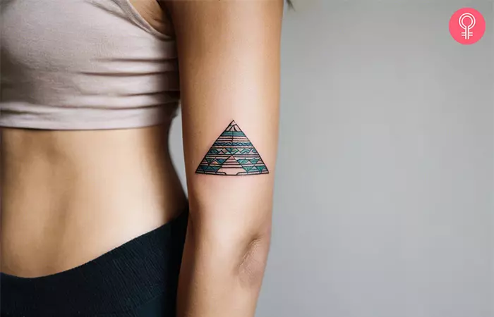 Woman wearing a simple pyramid tattoo on the upper arm