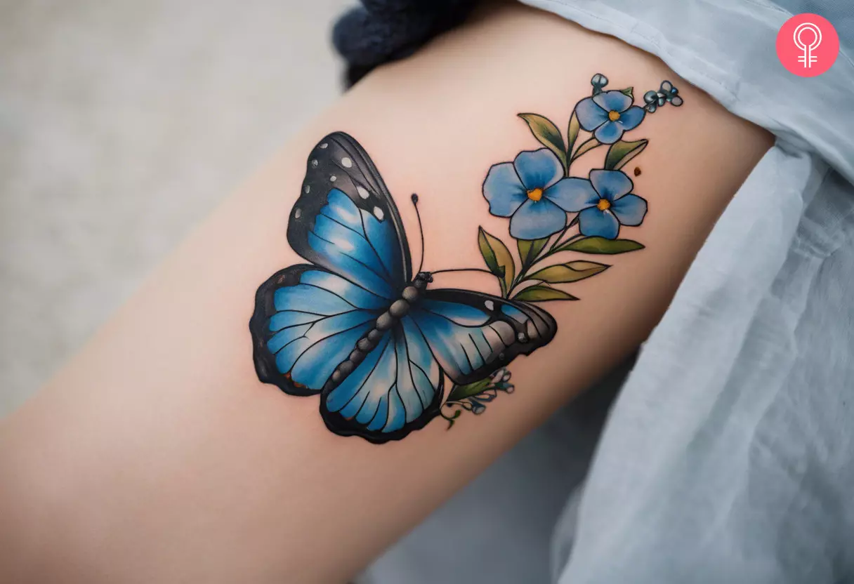 Woman with a forget me not flower with butterfly tattoo on the arm