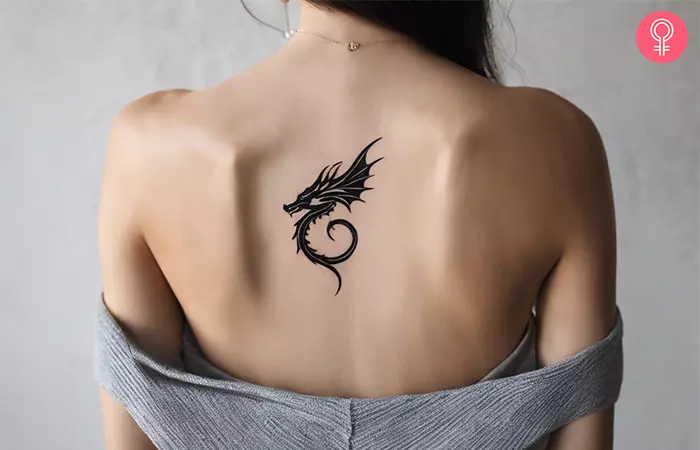 Woman with a small dragon back tattoo