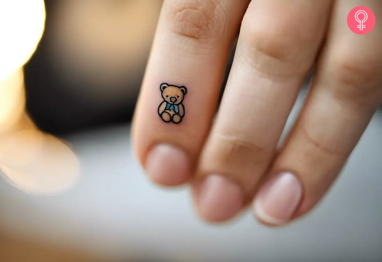 Woman with a small teddy bear tattoo on her finger