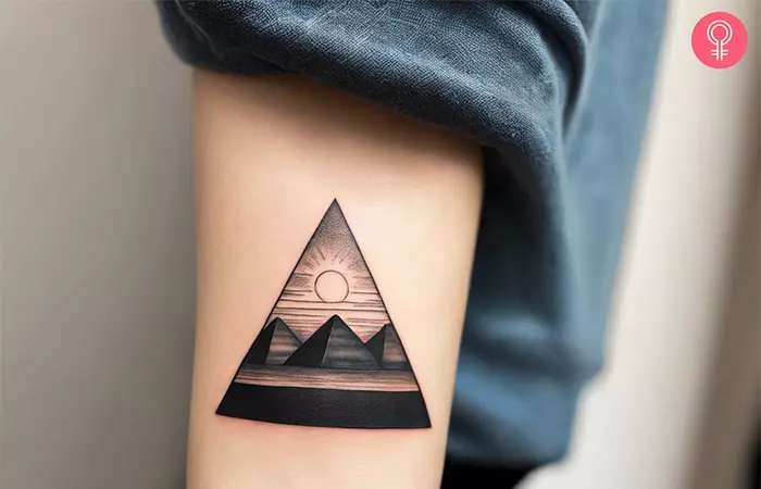 Woman with an Egyptian pyramids tattoo on the forearm