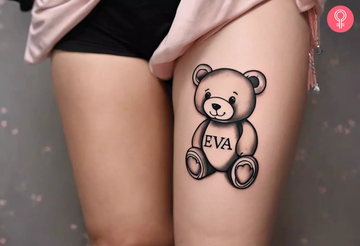 Woman with tattoo of a baby teddy bear with name on her thigh