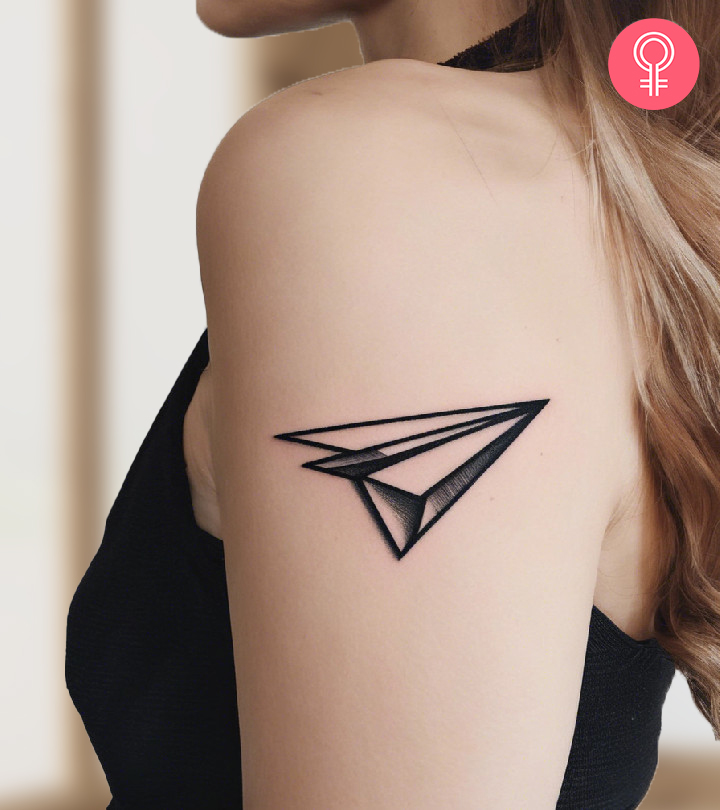 A paper airplane tattoo on a woman’s arm