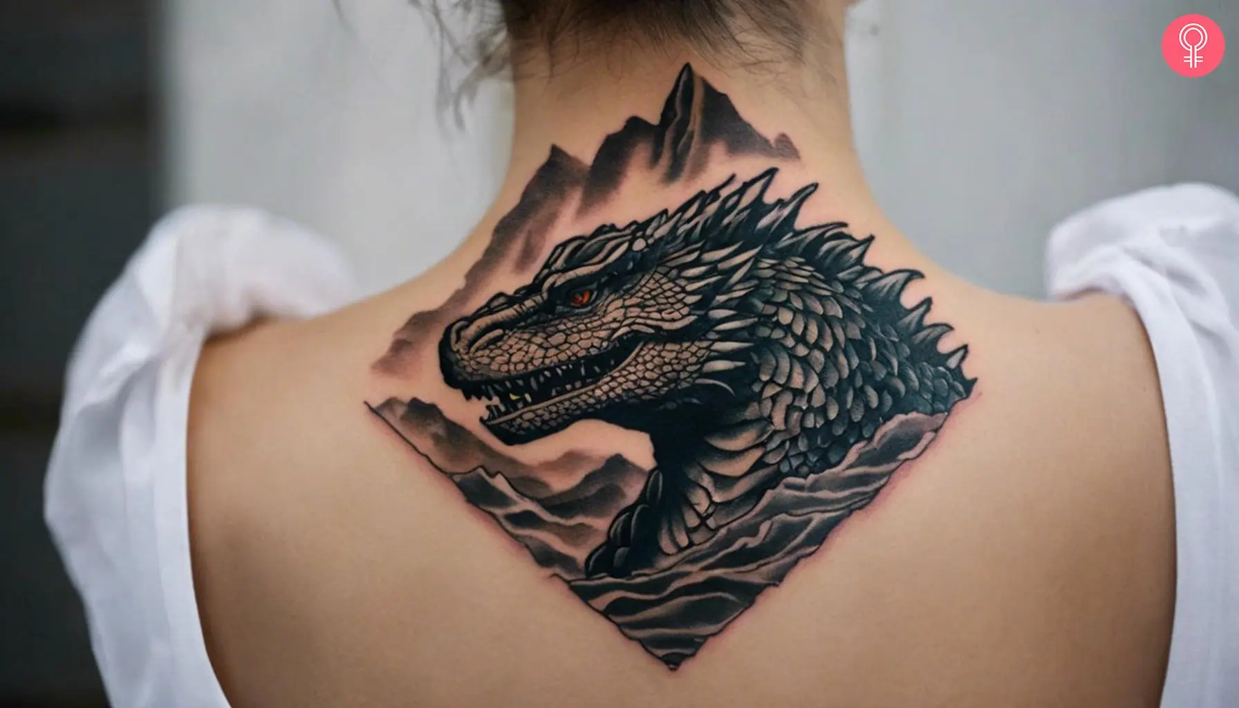 A Godzilla head tattoo design on a woman’s back