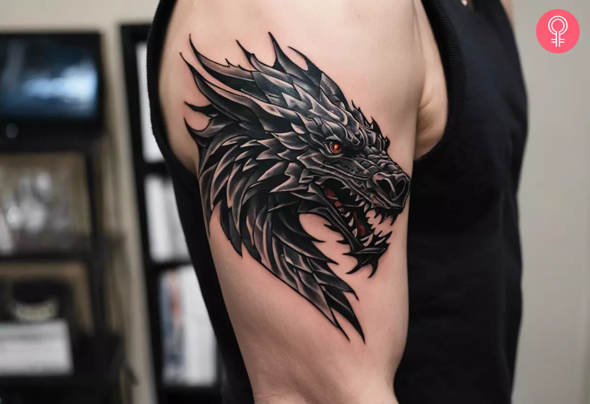 A black ink Game of Thrones dragon head tattoo on the upper arm
