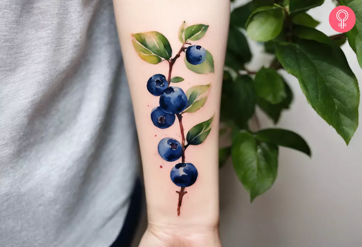 A blueberry branch tattoo on the forearm of a woman