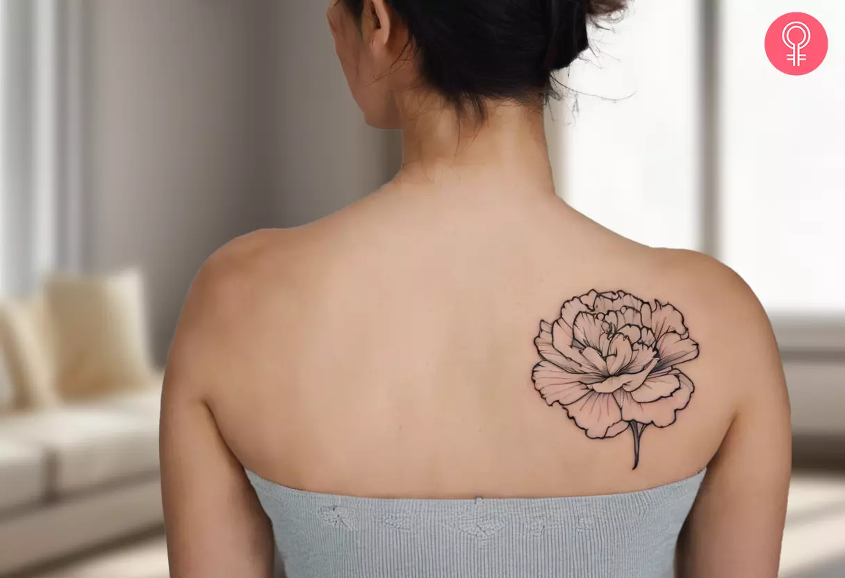 A carnation outline tattoo on a woman’s upper back