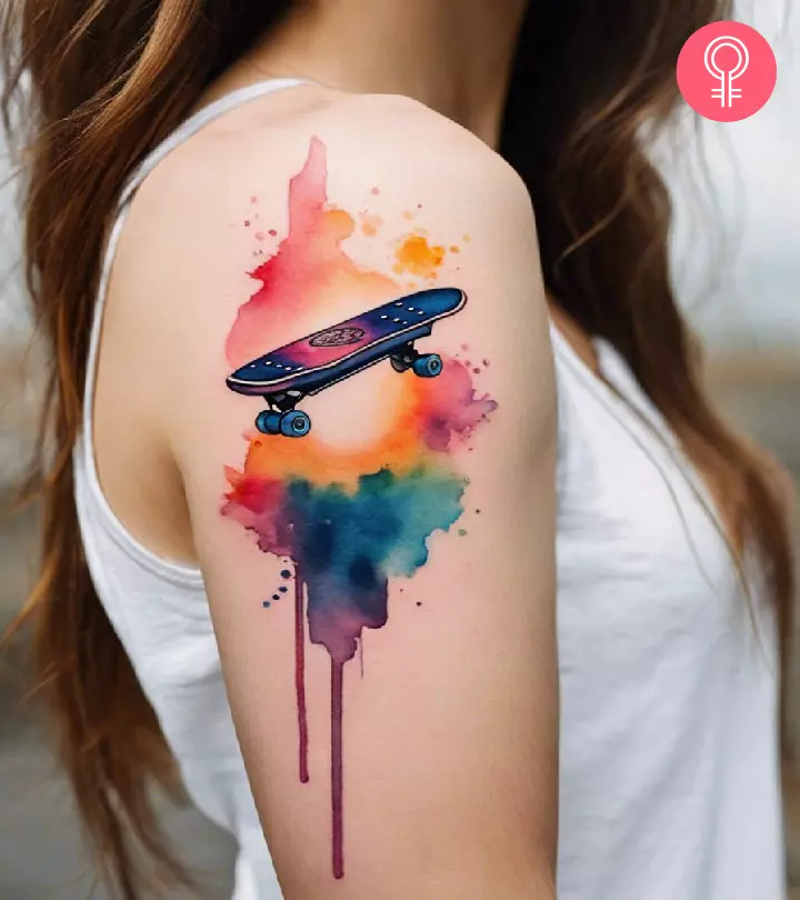 A colorful watercolor skateboard tattoo on the upper arm