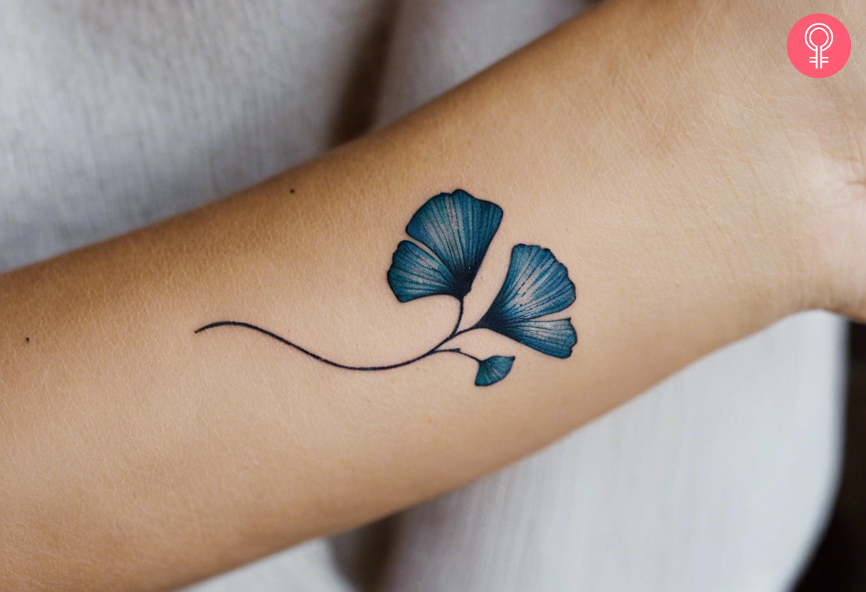 A cute and small Gingko leaf tattoo design in blue ink on the wrist