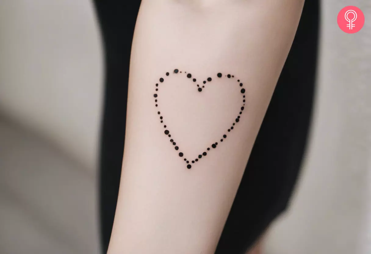 A dotted heart tattoo on the forearm