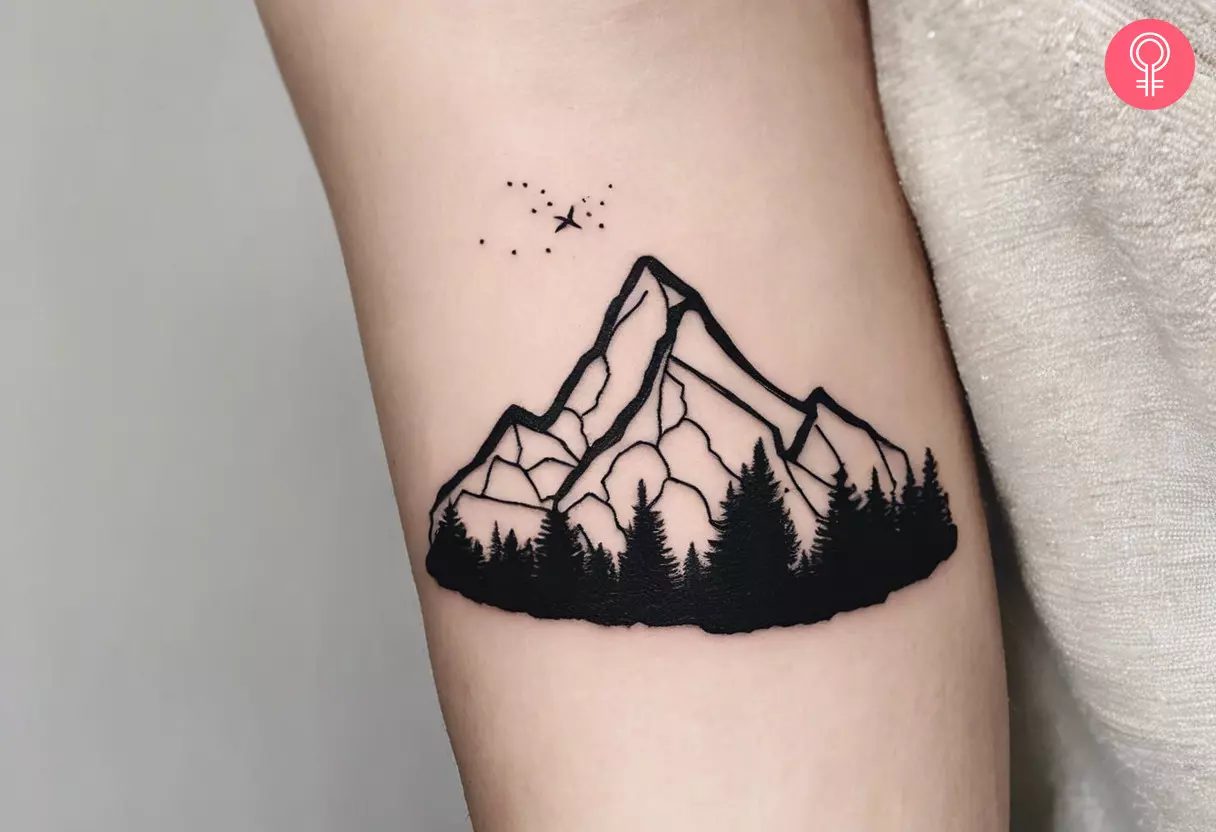 A line-art tattoo of a mountain on the arm