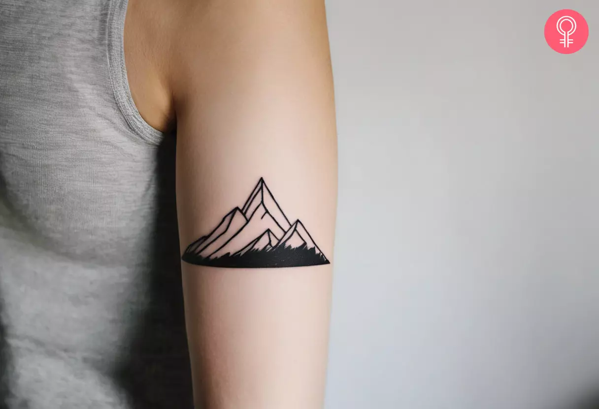 A line-art tattoo of a mountain on the upper arm