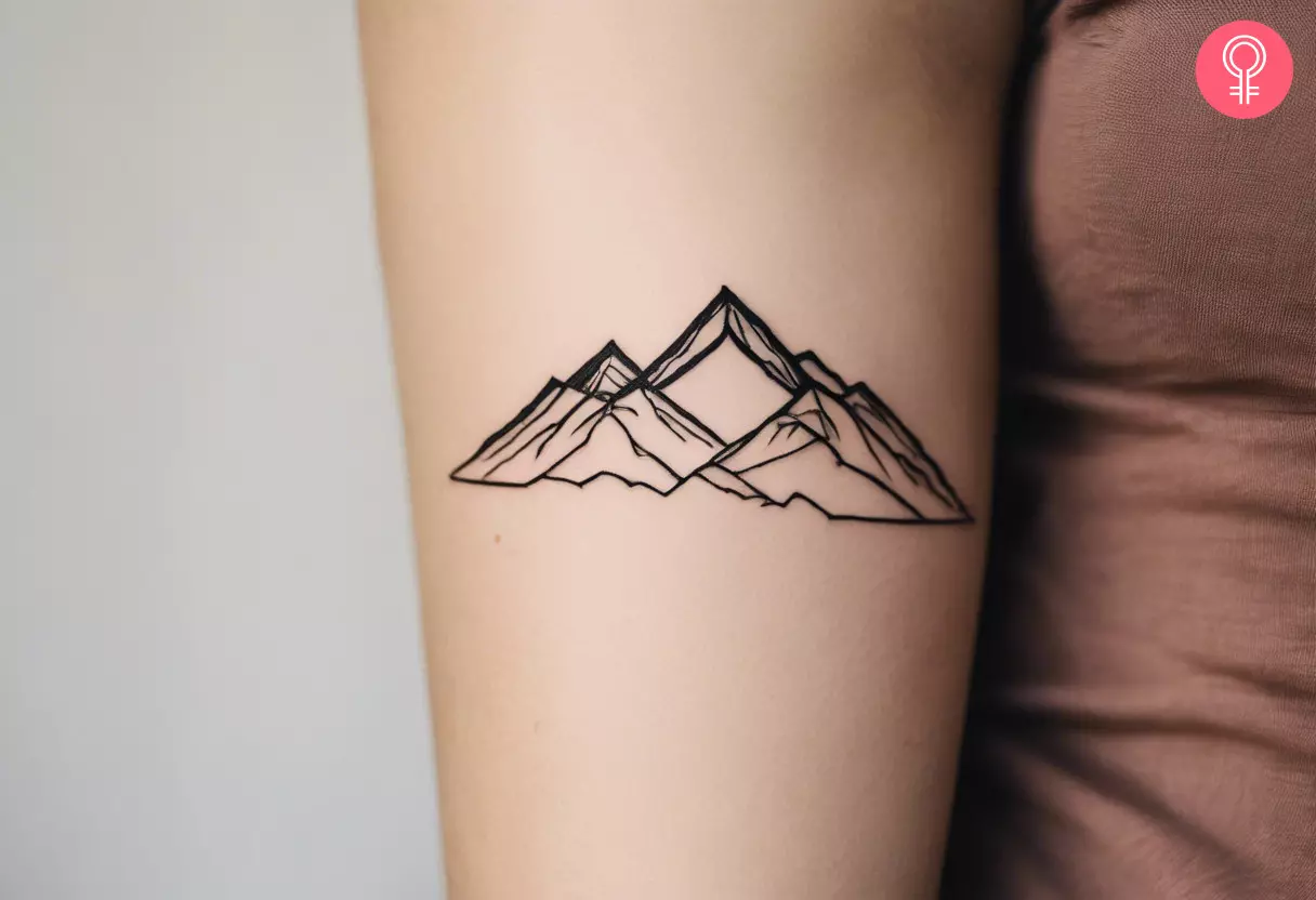 A line-art tattoo of a mountain on the upper arm