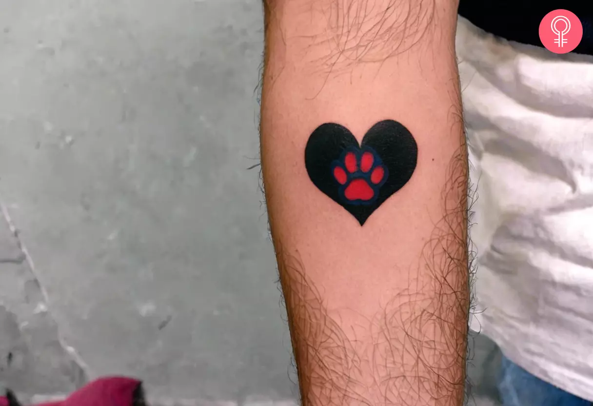 A man with a paw print heart tattoo on the lower arm