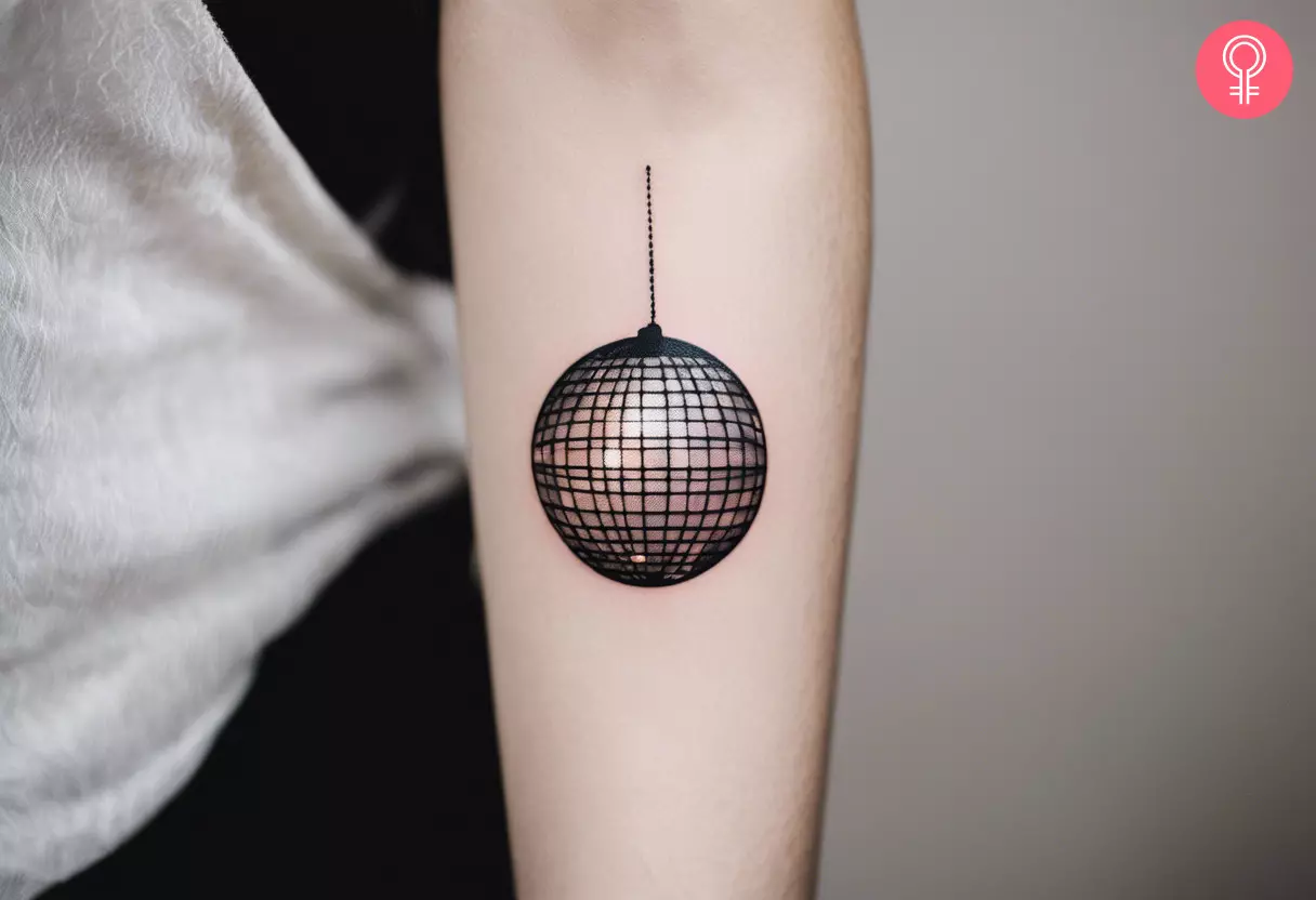 A minimalist disco ball tattoo on the forearm