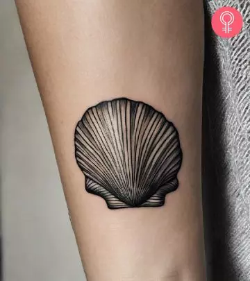 A woman with a black seashell tattoo on her upper arm