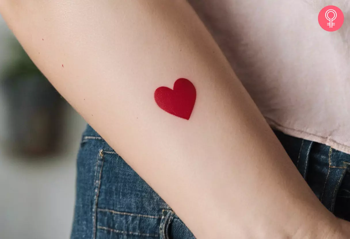 A red heart tattoo on the forearm