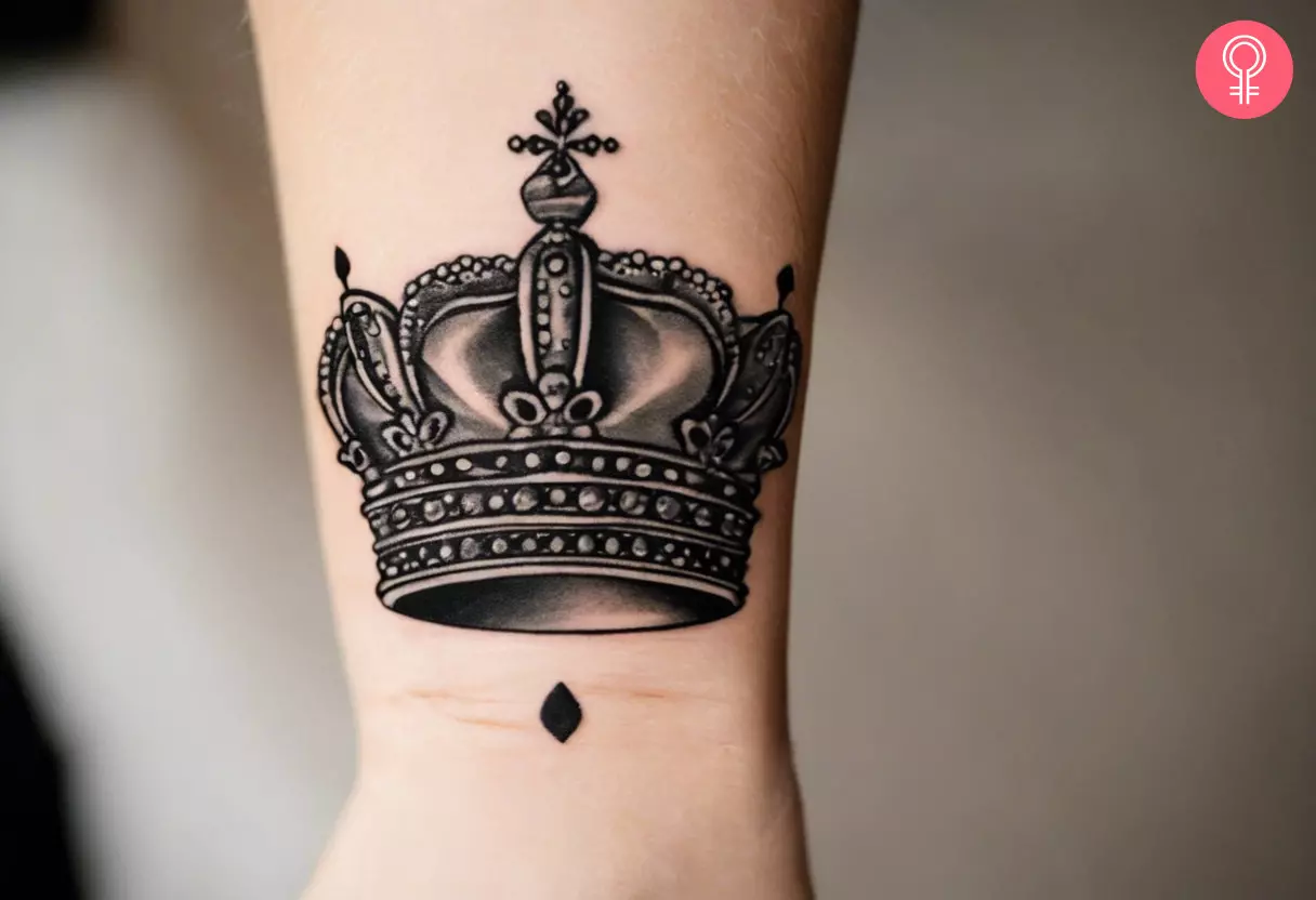 A simple queen crown tattoo on a woman’s wrist