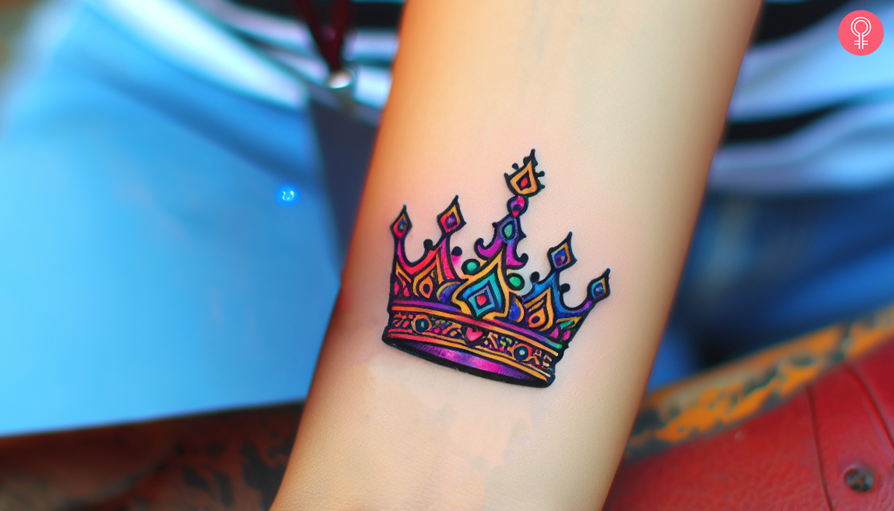 A small graffiti tattoo on a woman’s forearm featuring a crown