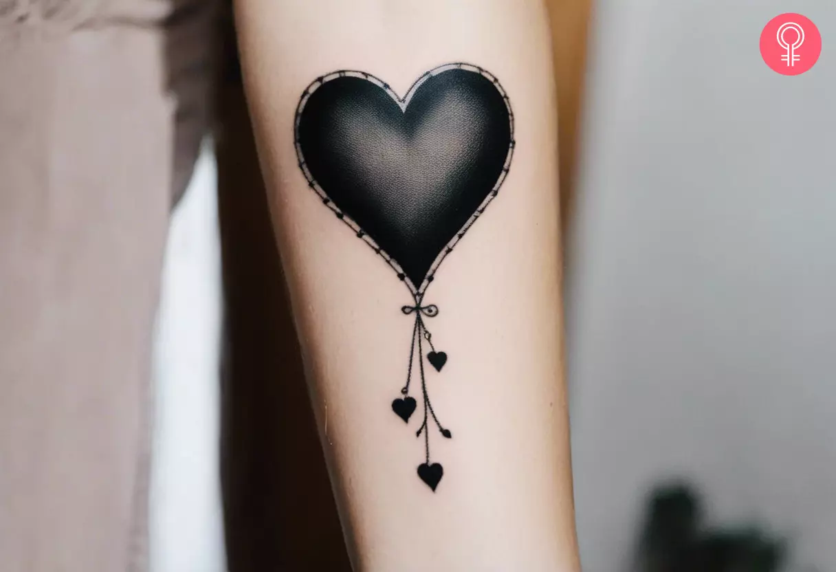A traditional black heart tattoo on the forearm