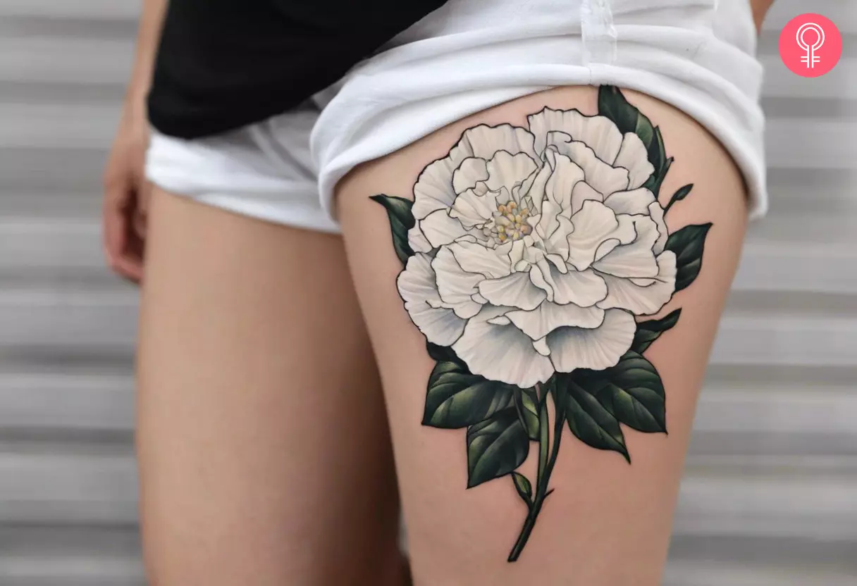 A white carnation tattoo on a woman’s thigh