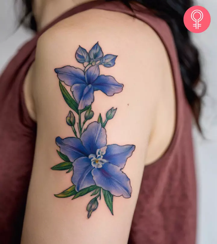 A woman with a colored larkspur tattoo on her upper arm
