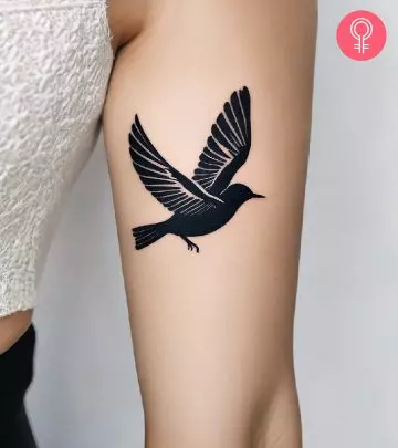 A woman with a minimalist tattoo of a Phoenix in black ink.