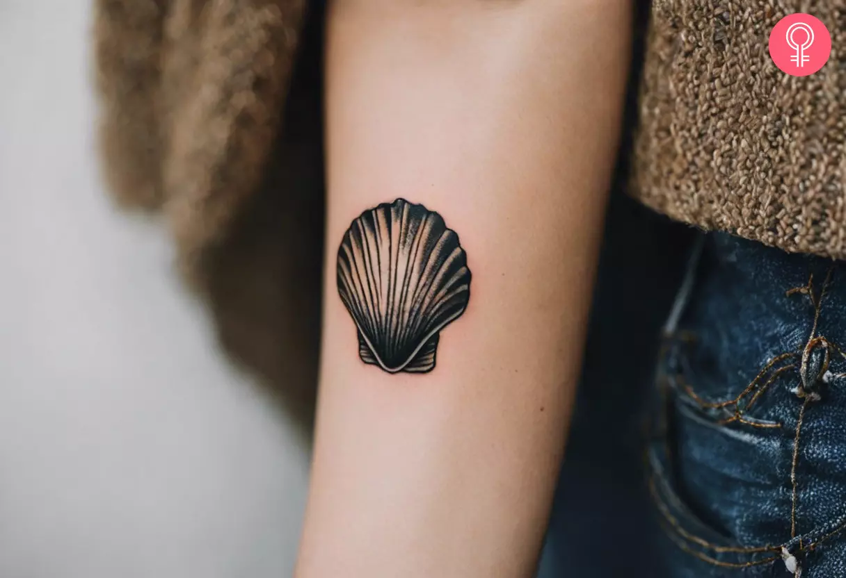 A woman with a vintage-style seashell tattoo on her arm