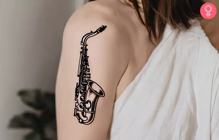 A woman with an outline saxophone tattoo on her bicep