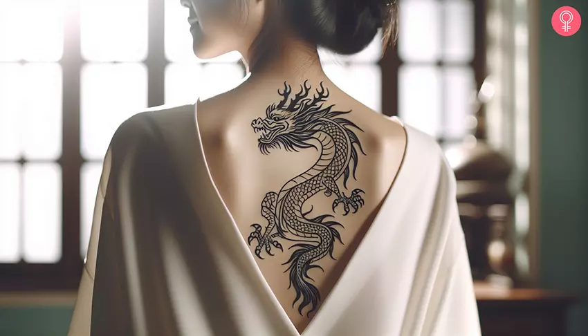 An intricate black ink dragon tattoo on the back of a woman
