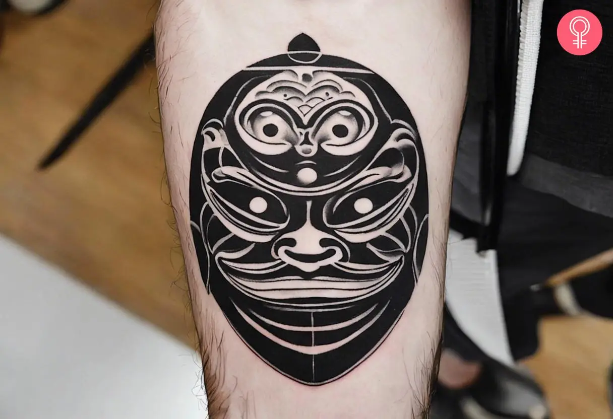 Black and white Daruma doll tattoo on the arm