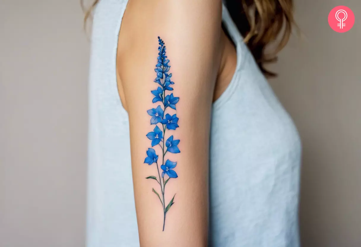 Woman with a blue delphinium tattoo on the upper arm